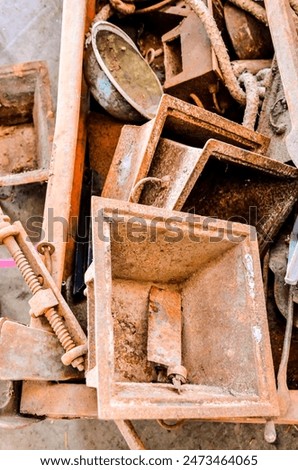 A pile of rusty metal objects, including a large metal box, a metal bowl, and a metal bucket