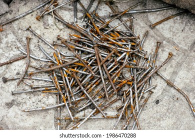 A pile of rusty nails lies on a stone tiles