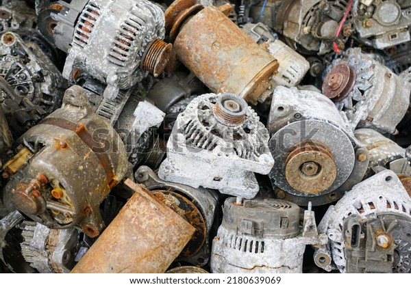 A pile of rusty and oxidized used car\
starters and alternators, scrap electric\
motors
