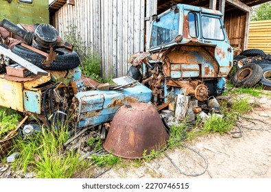 A pile of rusty scrap metal and truck tires in the backyard of a farm in summer - Powered by Shutterstock