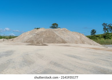 A pile of sandy gravel stockpiled at a quarry to be used in construction. Blue sky above.