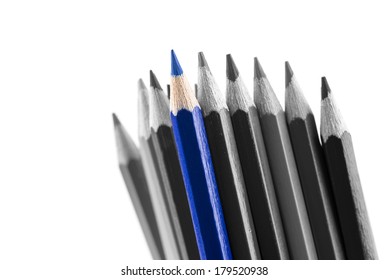 Pile of sharp colored pencils, with different hues, from black to light grey and a blue outstanding one, close-up on white background.