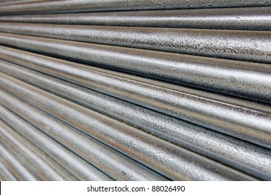 Pile of shiny galvanized steel pipe diminishing from right to left