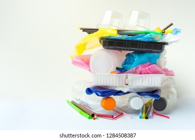 A Pile Of Single Use Plastic Garbage Including  Water Bottles, Drinking Straws, Food Packages And Carrier Bags On White Background With Copy Space. Pollution Concept.