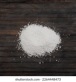 Pile of Sodium benzoate, sodium salt of benzoic acid on wooden surface, close-up. White crystalline powder, C6H5COONa. Food additive E211, Preservative.
