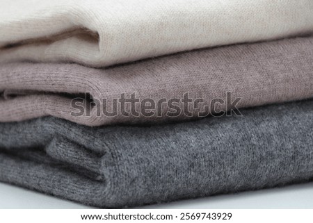 Pile or stack of neutral colors, folded cashmere or merino wool jumpers.