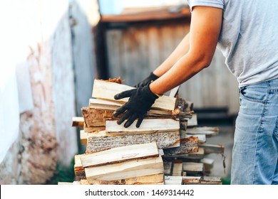 A pile of stacked firewood, prepared for heating the house. Gathering fire wood for winter or bonfire. Man holds fire wood in hands. - Powered by Shutterstock