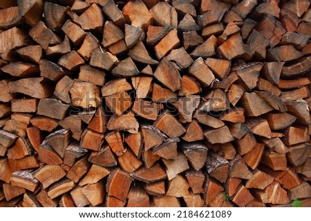 A pile of stacked firewood, prepared for heating the house. Gathering fire wood for winter or bonfire. Man holds fire wood in hand