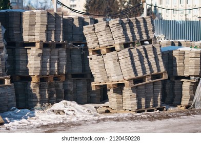 Pile Of Stacked Pallets With Paving Stones. Outdoor Storage Of Paving Slabs In Winter. Dangerous Critical Tilt Of The Pallet. The Concept Of A Threat To The Safety Of Life And Human Health.