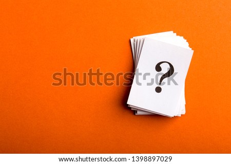 Pile of stacked question marks printed on sheets of white paper or signs arranged to the side on a orange background with copy space in a conceptual image.