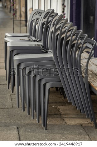 Pile of stacking silver gray plastic chairs are beside of The cafe terrace at sunny day. Detailed of pattern stack plastic chairs, Space for text, Selective focus.