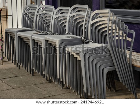 Pile of stacking silver gray plastic chairs are beside of The cafe terrace at sunny day. Detailed of pattern stack plastic chairs, Space for text, Selective focus.
