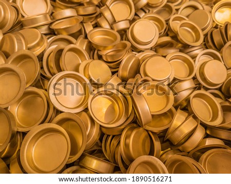 pile of stamped thin sheet brass hat-shaped semimanufatures, closeup with selective focus and blur