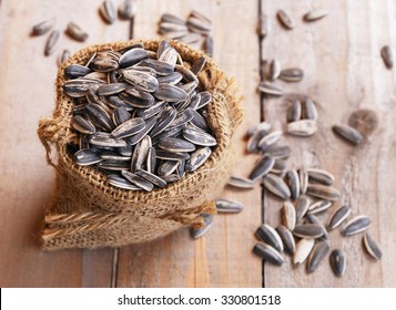  pile of sunflower seeds in the small sack on the wooden background 