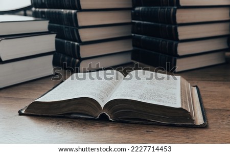 A pile of thick books on the table. Open book
