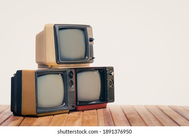 Pile of three old vintage TVs on wooden table isolated on white background.
