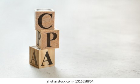 Pile with three wooden cubes - letters CPA meaning COST PER ACTION / ACQUISITION on them, space for more text / images at right side.