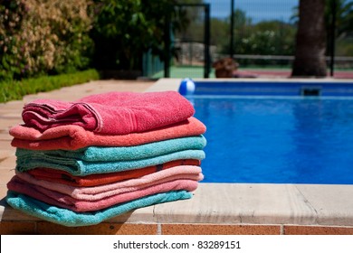 A Pile Of Towels Beside A Beautiful Pool