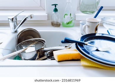 pile unwashed dishes in kitchen sink, in home kitchen with windows, routine, household chores