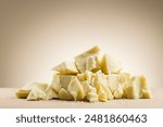 Pile of white chocolate flakes on cream colored background.