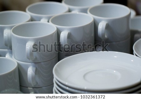 pile of white clean cups and saucers in a public cafe, prepared for tea or coffee