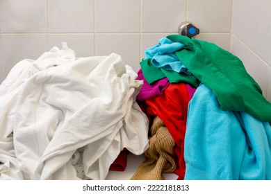 Pile of white and colors clothes being separate before load in to watching machine. Sort laundry before washing concept.