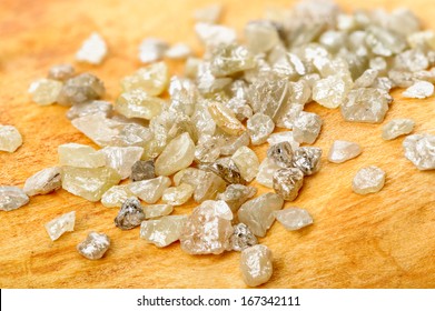 A Pile Of White Grey Uncut And Rough Diamonds On Birch Wood