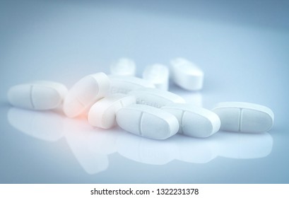 Pile Of White Oblong Tablets Pills On Gradient Background. Pharmaceutical Industry. Pharmacy Product. Global Healthcare. Drug In Pharmacy Drugstore Or Hospital. Drug Use In Pregnancy And Lactation.