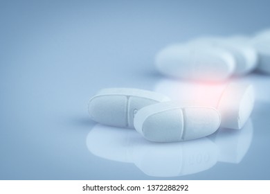 Pile Of White Oblong Tablets Pills On Gradient Background. Pharmaceutical Industry. Pharmacy Product. Global Healthcare. Drug In Pharmacy Drugstore Or Hospital. Drug Use In Pregnancy And Lactation.