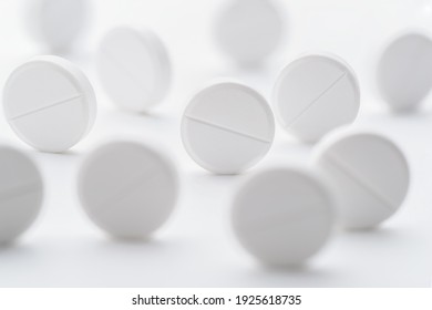A pile of white pills scattered on a bright white background. Selective focus. Mockup layout, template.