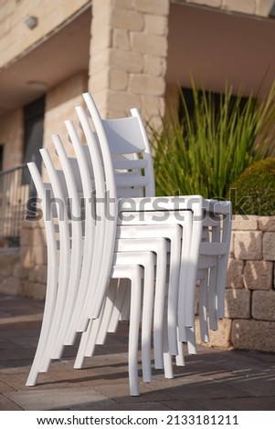 pile of white plastic chairs in the gardenm,detailed of pattern stacks plastic white chairs.