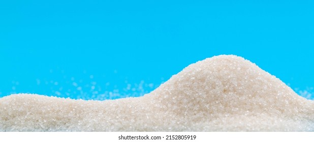 Pile Of White Sugar Crystals On Blue Background.