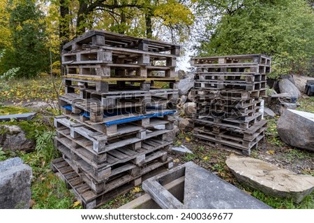 pile of wooden pallets between granite stones and boulders sorrounded by trees.