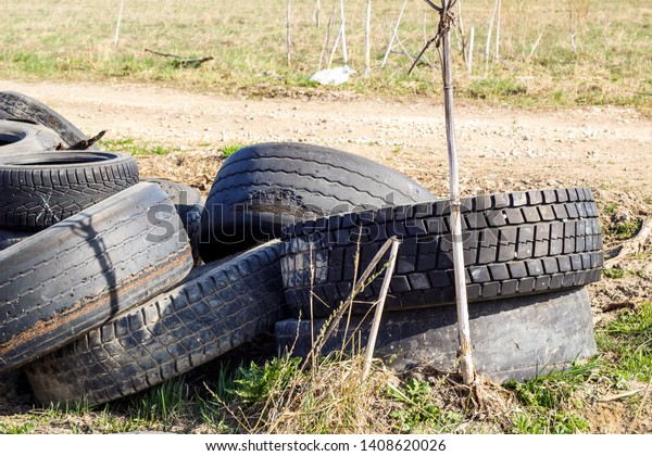 A pile of\
worn car tires dumped on the field. Environmental pollution.\
Landfill of used tires, car\
waste.