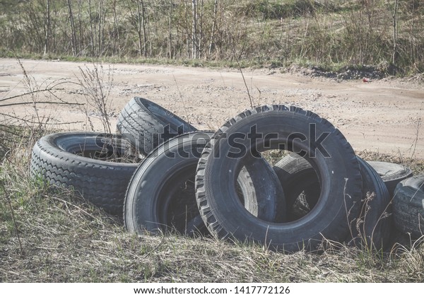 A pile of\
worn car tires dumped on the field. Environmental pollution.\
Landfill of used tires, car waste. Car waste recycling, automotive\
industry. Rubbish along the\
road