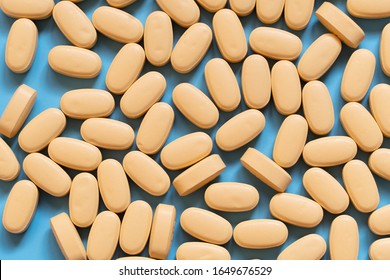 Pile Of Yellow Medicine Tablets On Blue Background. Lopinavir/Ritonavir Combination Tablets For The Treatment And Prevention Of HIV/AIDS. Top View.