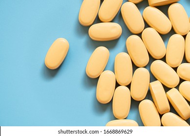 Pile Of Yellow Medicine Tablets On Blue Background. Lopinavir/Ritonavir Combination Tablets For The Treatment And Prevention Of HIV/AIDS. Top View.