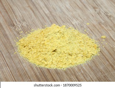 A pile of yellow nutritional yeast on a cutting board.