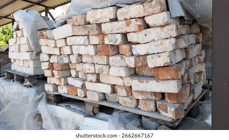 Piled bricks on pallets, wrapped in plastic for protection, displaying diverse colors and textures, ideal for construction and renovation projects