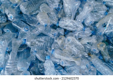 Piles of clear blue plastic drinking bottles are collected for recycling so as not to pollute the environment and prevent climate change. - Shutterstock ID 2129602370
