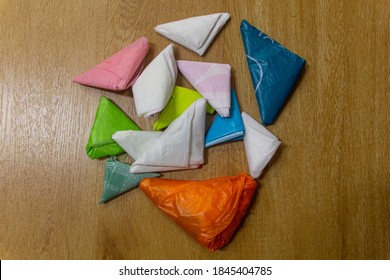 Piles Of Colorful Plastic Bags That Are Folded Into Triangular Shapes, Fold Plastic Bags For Reuse ,  Reduce Using Plastic Bags. Wooden Floor As Background