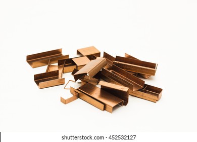 Piles of copper office staples isolated on white background