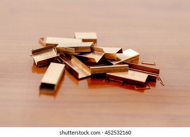 Piles of copper office staples on wooden background