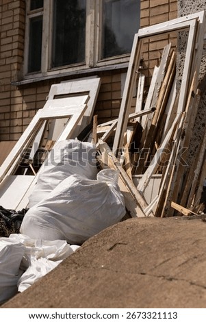 Piles of garbage and discarded construction materials are situated against a brick building. White bags are stacked alongside wooden frames, indicating recent renovation work. 3D Illustration
