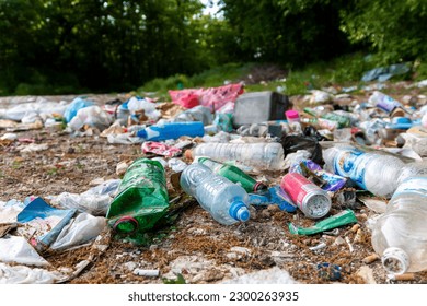 Piles of garbage in the forest, random dumping in nature. Stink heap, plastic bag and bottles, rubbish in polluted green  grass of nature landscape background. The concept of human pollution of forest