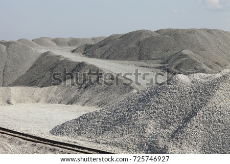 Piles of limestone rocks with the railroad in the foreground. Gravel hills. Mining industry.