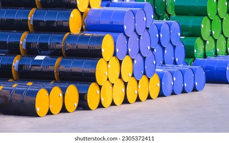 Piles of many various 200-litre oil drums stacked on the patio outside of industrial building in perspective side view