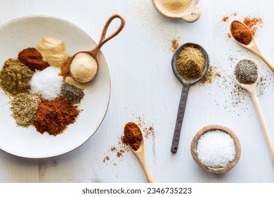 Piles of spices on various spoons and a plate with copy space in the middle. - Powered by Shutterstock