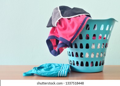 Piles Of Sport Cloths In Laundry Basket In Blue Background. Messy, Cluttered Most Active Teenager Room.
