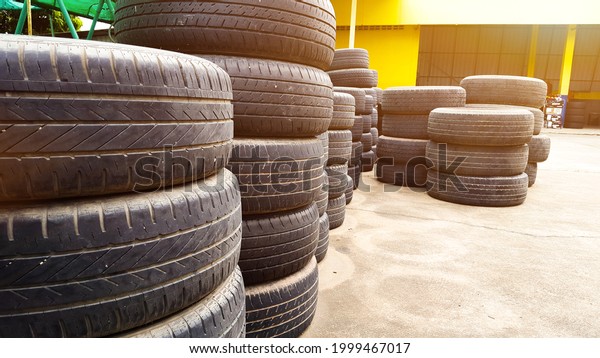 Piles of used car tires at a car maintenance\
garage, waiting for persons to buy at low prices, edited with lens\
flare and enhanced colors. Concept for saving natural resources and\
our environments
